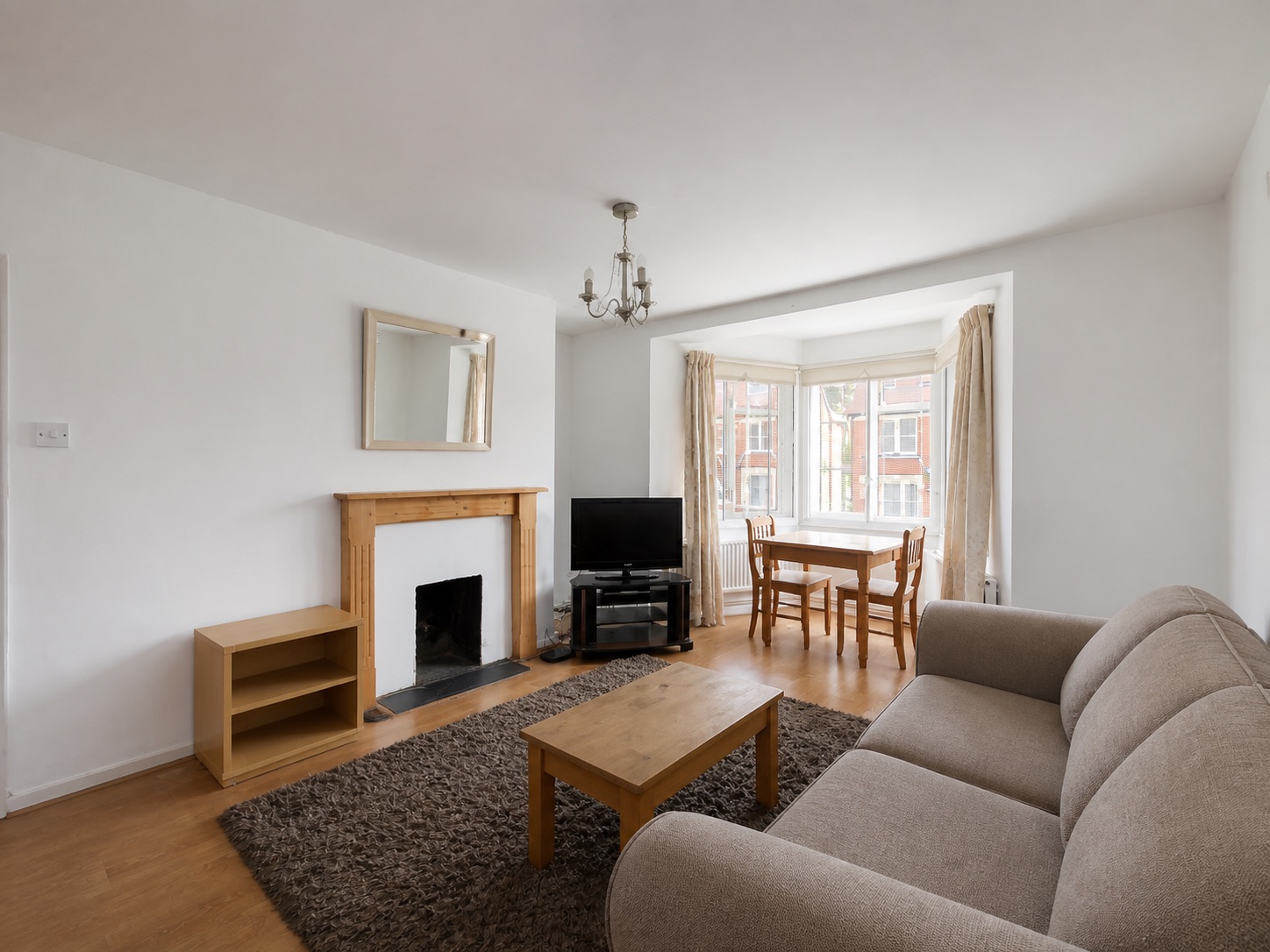 Das ursprüngliche Wohnzimmer mit Sofa, Kamin und Erkerfenster.